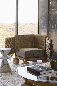 A natural-fiber chair sits in a modern living room with a view.