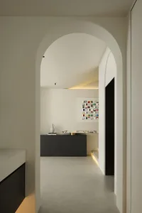 A minimalist interior with concrete walls and floor, featuring a black cabinet and a colorful abstract painting.