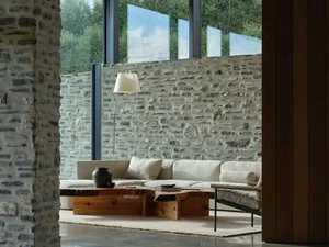 Contemporary minimalist living room featuring a concrete wall and floor, with a comfortable sofa and a wooden coffee table in