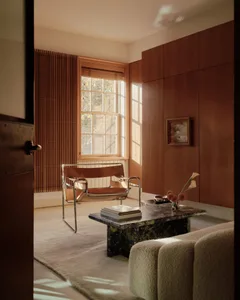 A minimalist residential living room with wood accents and a window letting in natural light.