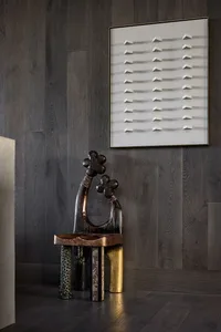 A modern artwork featuring metallic elements against a wooden wall background.