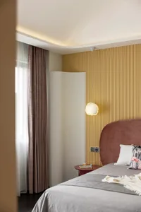 Modern bedroom featuring a velvet headboard and wooden paneling on the wall with soft lighting and a cozy atmosphere.