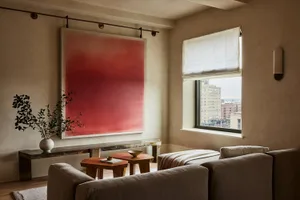 Modern living room featuring neutral-colored sofas, marble top coffee tables, and a large abstract red painting