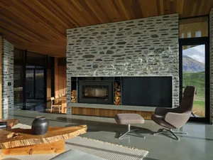Modern living room featuring a stone fireplace wall with a wood floor and glass window.