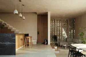 A minimalist living space featuring concrete walls, wood flooring, and glass elements.