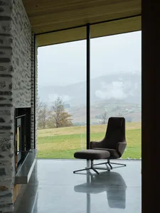 A modern residential space featuring minimalist furniture, a fireplace, and a large window with a view of the mountains.