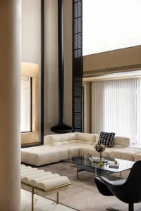 Modern white leather sectional sofa in a contemporary living room with high ceilings and large windows.