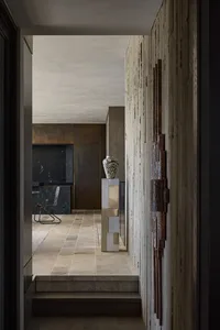 Modern interior corridor featuring metallic walls, wooden furniture, and concrete flooring.