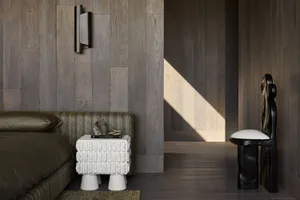 A modern bedroom with dark wooden walls and flooring, featuring a contemporary bed and minimalist furniture.
