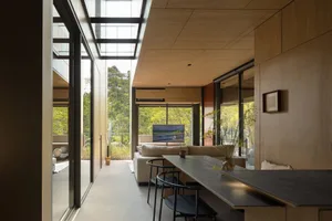 A modern living room featuring natural light, wood finishes, and a comfortable seating area.