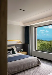 Modern minimalist bedroom featuring a textured white wallpaper wall, wooden floor, and large window with a view of greenery a