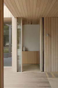 Modern minimalist entryway with wooden walls and large glass window.