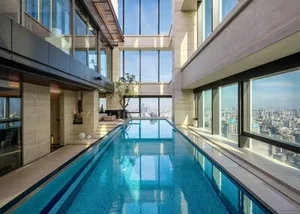 Indoor swimming pool with glass walls overlooking a cityscape.