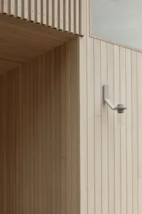 Modern architectural design featuring a white wooden exterior with natural wood grain and a white sconce light fixture.