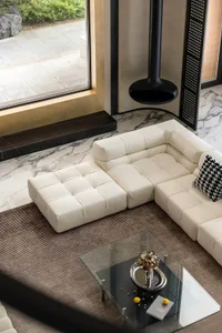 Modern living room featuring a white leather sectional sofa with a glass coffee table and marble flooring.