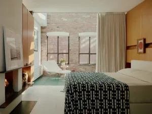 A minimalist bedroom with brick walls, white flooring, and a wooden headboard.