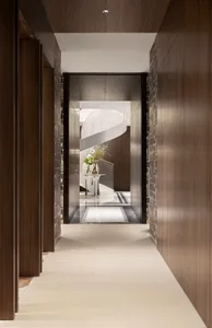 A long, narrow corridor with wooden walls and floors, featuring a staircase and a flower arrangement on a small table.