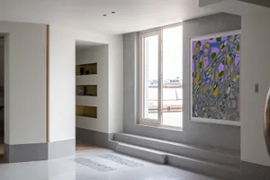 A modern living room with concrete flooring, large windows, and abstract art.
