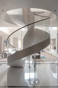 Modern, stylish, and elegant white spiral staircase with glass railings and a circular ceiling design in a contemporary inter