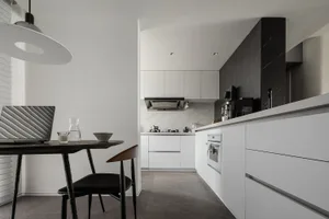 Modern kitchen with marble countertops, wooden accents, and high ceiling.