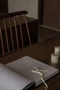 A cozy home office setup featuring a wooden desk, a book, and candles, creating a warm and inviting atmosphere.