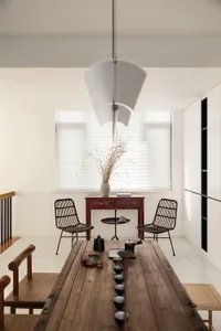A minimalistic living room featuring a wooden table with black ceramic tea cups and a white vase with dried plants by the win