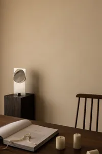 A minimalist interior design featuring a wooden table with candles and a book.