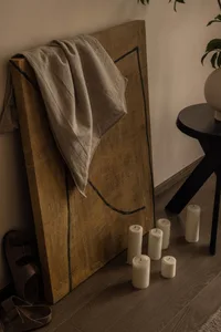A minimalist living room with candles and a textured wooden panel.