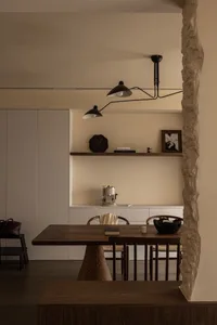 A modern dining room featuring a wooden table and chairs, with a minimalist design and a built-in shelf.