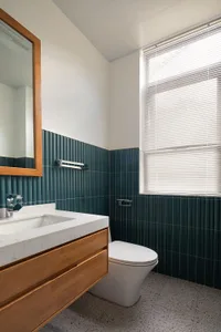 Modern bathroom interior with green tiles and wooden vanity.