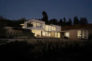 A modern house featuring a contemporary design with wooden accents, glass walls, and concrete structures.