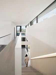 A modern indoor staircase with concrete steps, glass walls, and a view out to the outdoors.