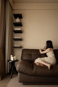 A woman sitting on a brown leather sofa in a cozy living room environment.