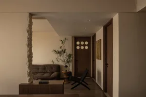 Modern minimalist living room with wooden furniture and a stone column.