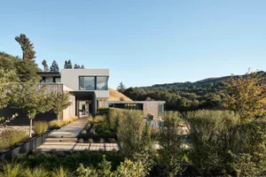 A modern minimalist residential exterior featuring glass windows and concrete materials.