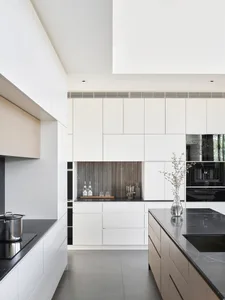 Modern kitchen featuring white marble countertops and aluminum appliances on black marble floor.