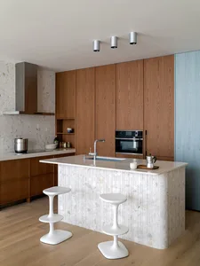 A modern residential kitchen featuring a large island with a terrazzo countertop and minimalist design.