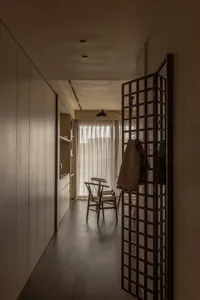 A minimalist residential interior featuring wooden tiles, a glass door, and neutral tone walls.
