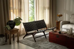 A cozy living room with a woven leather sofa, wooden table, and potted plant.