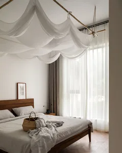 A minimalist bedroom featuring a bed with white curtains and a wooden headboard, minimalistic decor, and a serene atmosphere.