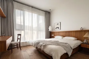 A minimalist bedroom featuring wooden furniture and a bed with white bedding and a wood headboard.