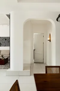 A minimalist, modern residential interior featuring clean lines, white plaster walls, and a wooden dining table.