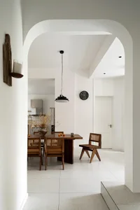 A modern minimalist dining room with wooden furniture and metallic accents.