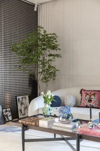 A modern living room featuring glass furniture, a white sofa, and a potted plant.