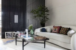 Modern living room featuring a white couch with decorative pillows, a glass and wood coffee table, and a white floor with a b