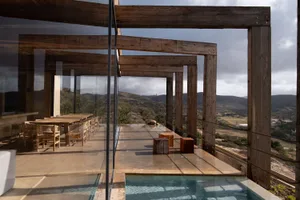 Minimalist architectural terrace featuring a glass pool surrounded by wood and concrete elements.
