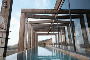 Modern, wood-framed poolside architecture with a glass wall.