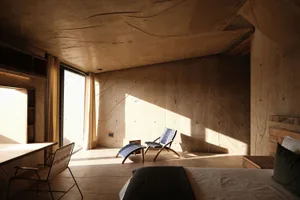 A minimalist bedroom with concrete walls, bench seating, and a bed.