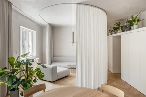 A minimalist living room with white cloth furniture and white curtains.