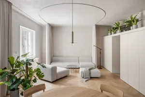 A modern minimalist living room with a white speedlight hanging from the ceiling.